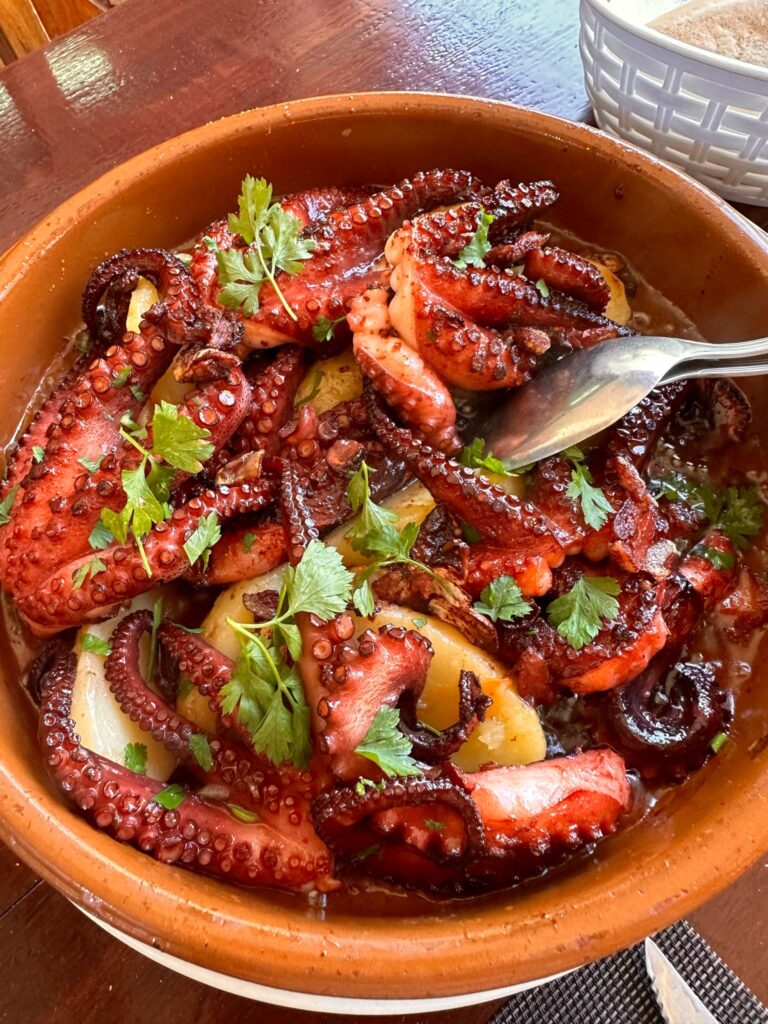 A bowl of octopus with peppers and herbs