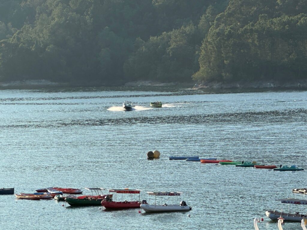 Calm water with small boats beneath wooded hills