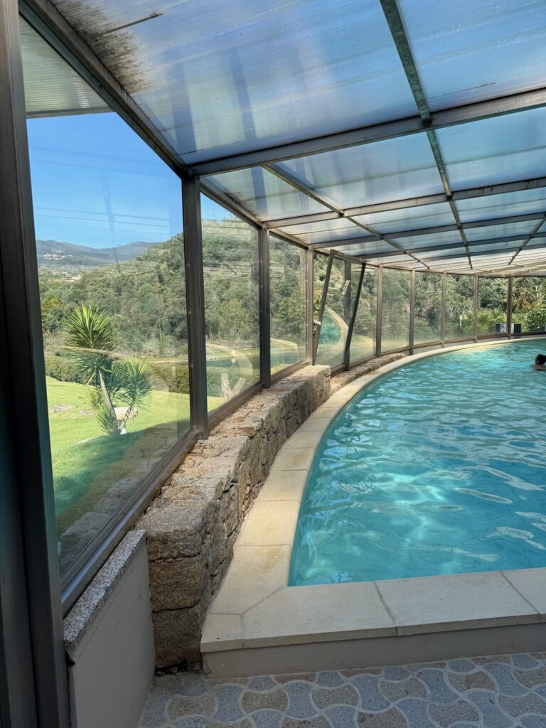 An indoor swimming pool with glass walls and views of the hills